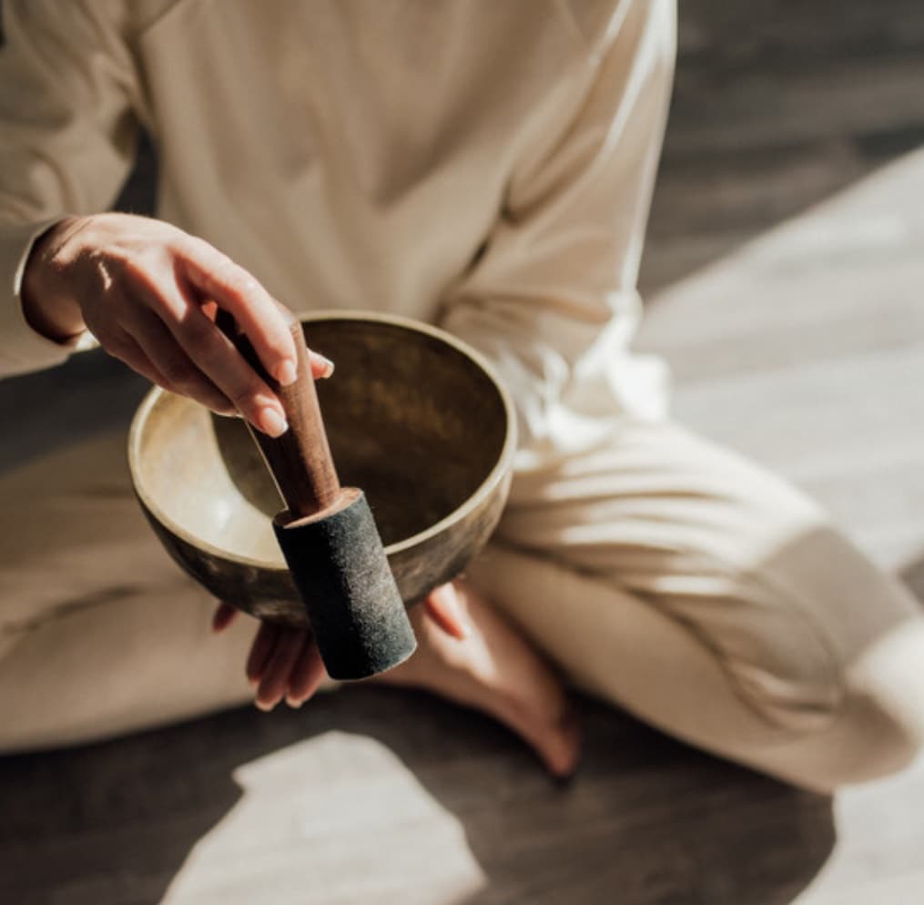 A practitioner sounding a singing bowl held in one hand